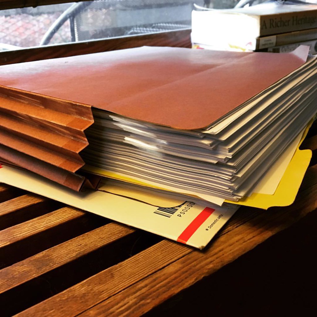Stack of grant application files on a desk, paperwork for Commonwealth Foundation grants