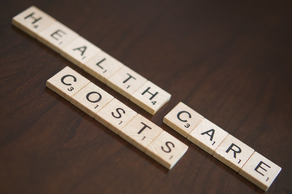 Letter tiles spelling health care costs, focus of the GFF x CIVIC VOICES grant