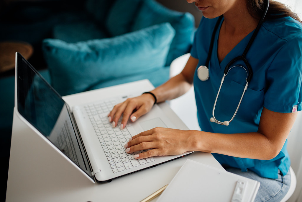 Healthcare worker updates digital patient records on a laptop for SHA compliance