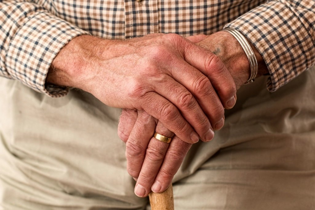 Older person resting both hands on a walking stick, marking International Day of Older Persons 2026