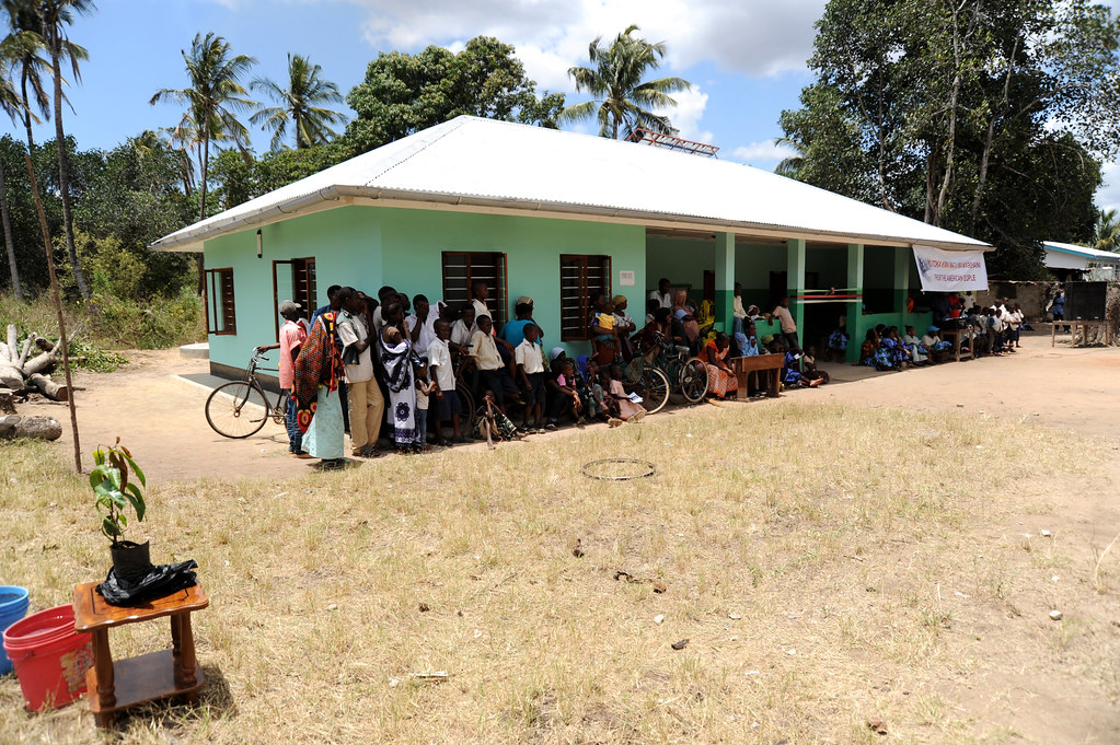 Village health clinic with residents gathered outside, illustrating community health promoters Kenya and SHA cover