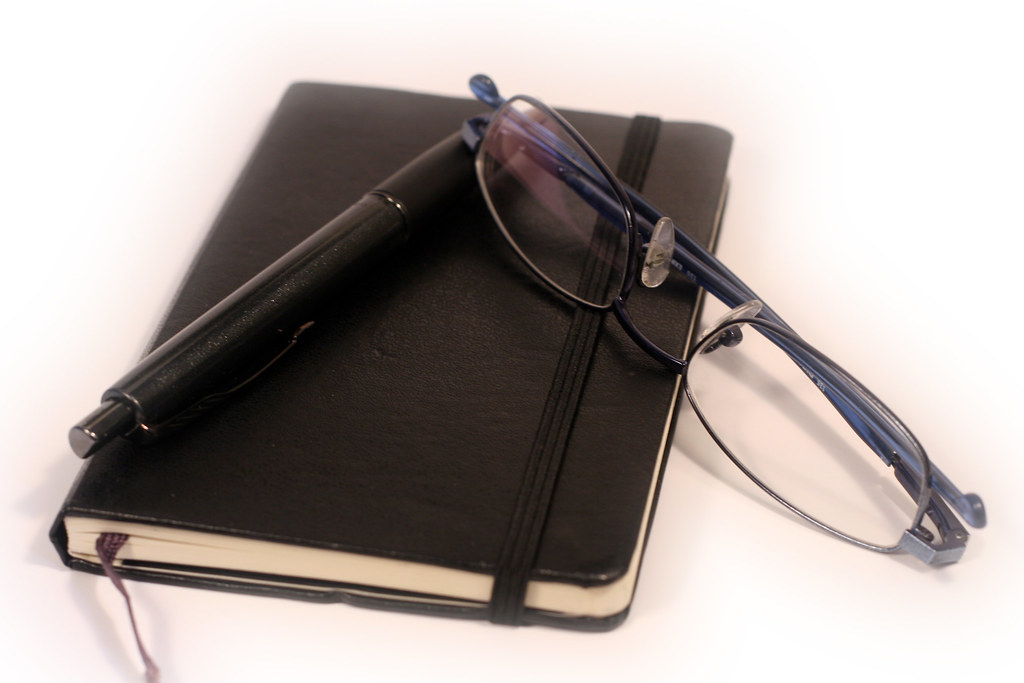 Pen, diary and glasses on a desk, used to plan an NGO monitoring and evaluation plan