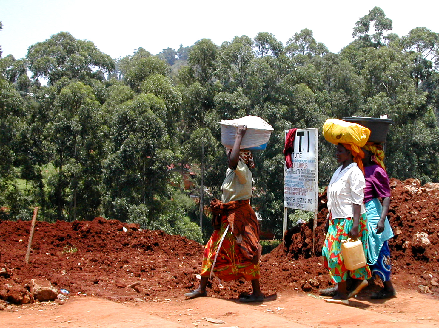 Women carrying loads and water home in Kenya, reflecting unpaid care work in Kenya